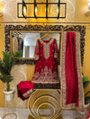 Red traditional outfit with gold details hanging on a decorative mirror in a room.