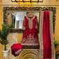 Red traditional outfit with gold details hanging on a decorative mirror in a room.